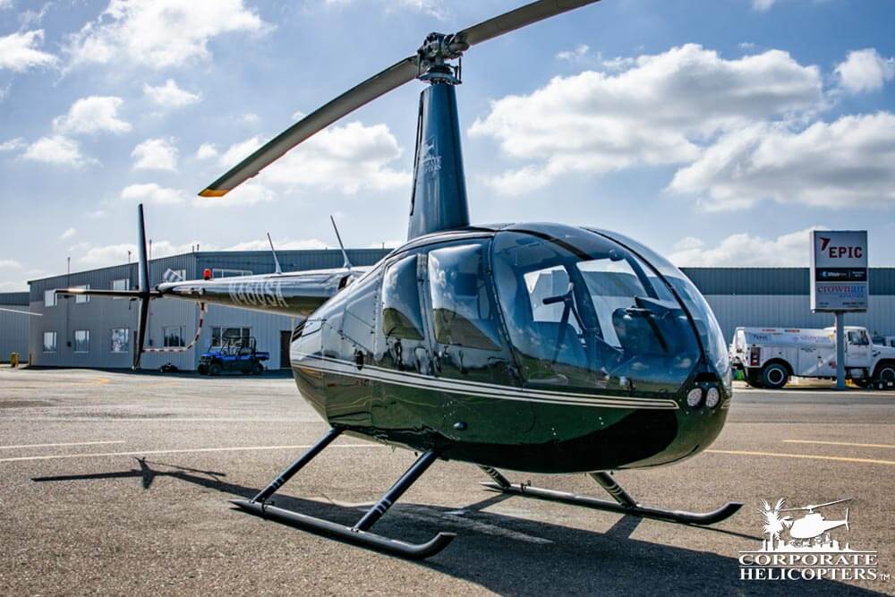 2006 Robinson R44 Raven II on an airfield. A fueling truck is in the background