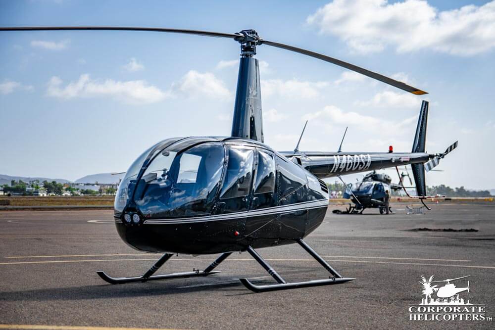 2006 Robinson R44 Raven II on an airfield, another helicopter sits in the distance