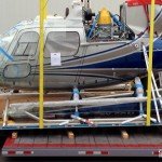 Side view: part of an AStar 350 B2 helicopter on a Pallet loading to flatbed trailer