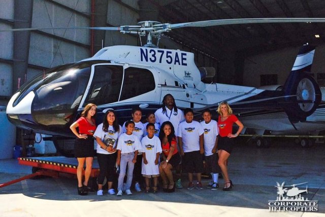 A group of people and kids stand in front of a helicopter