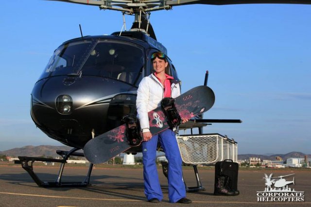 Snowboarder stands with snowboard in front of Astar fitted with a cargo basket