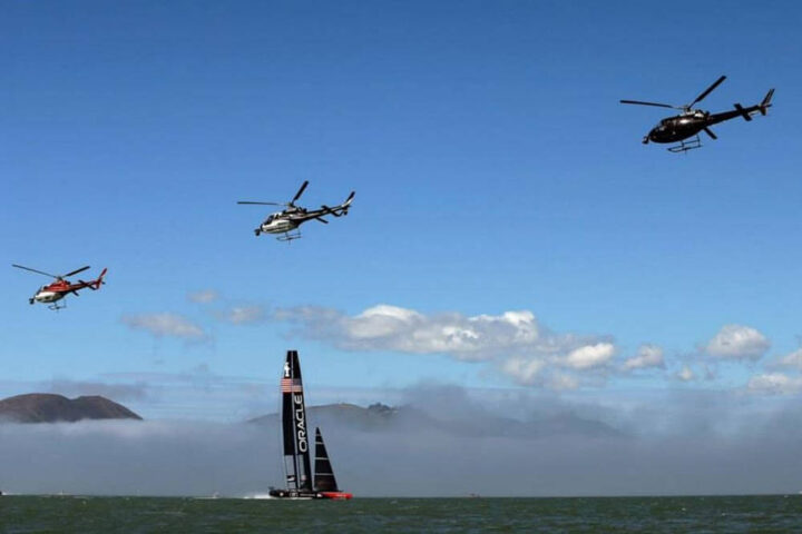 3 helicopters flying over a boat