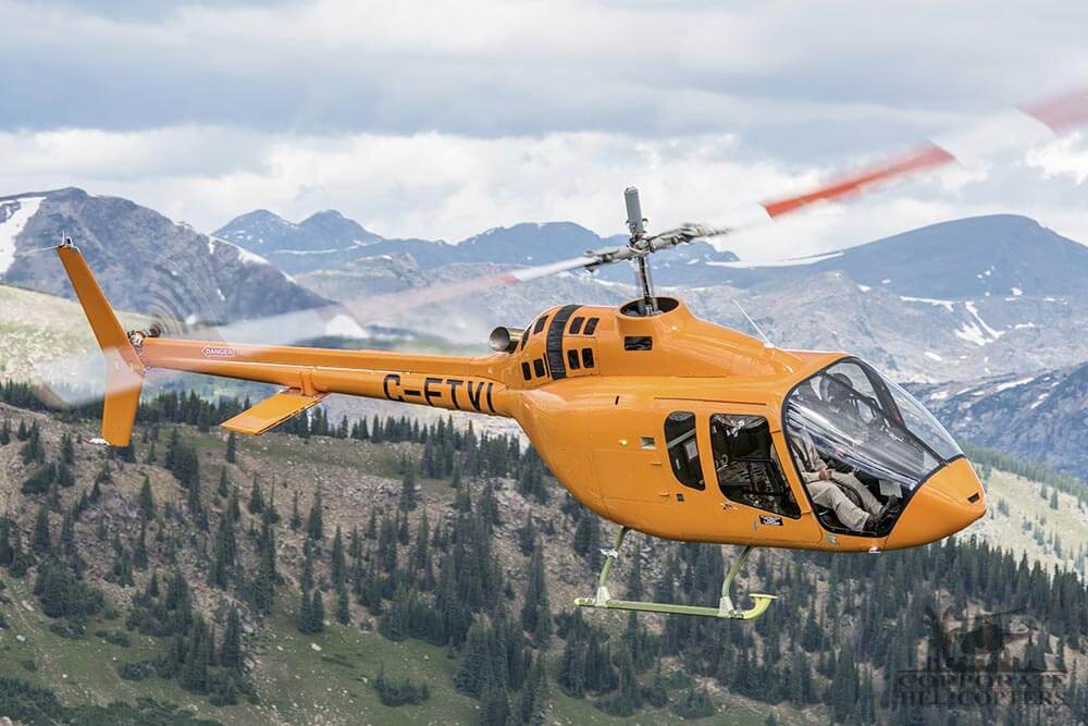 An orange Bell 505 Jet Ranger X helicopter in flight