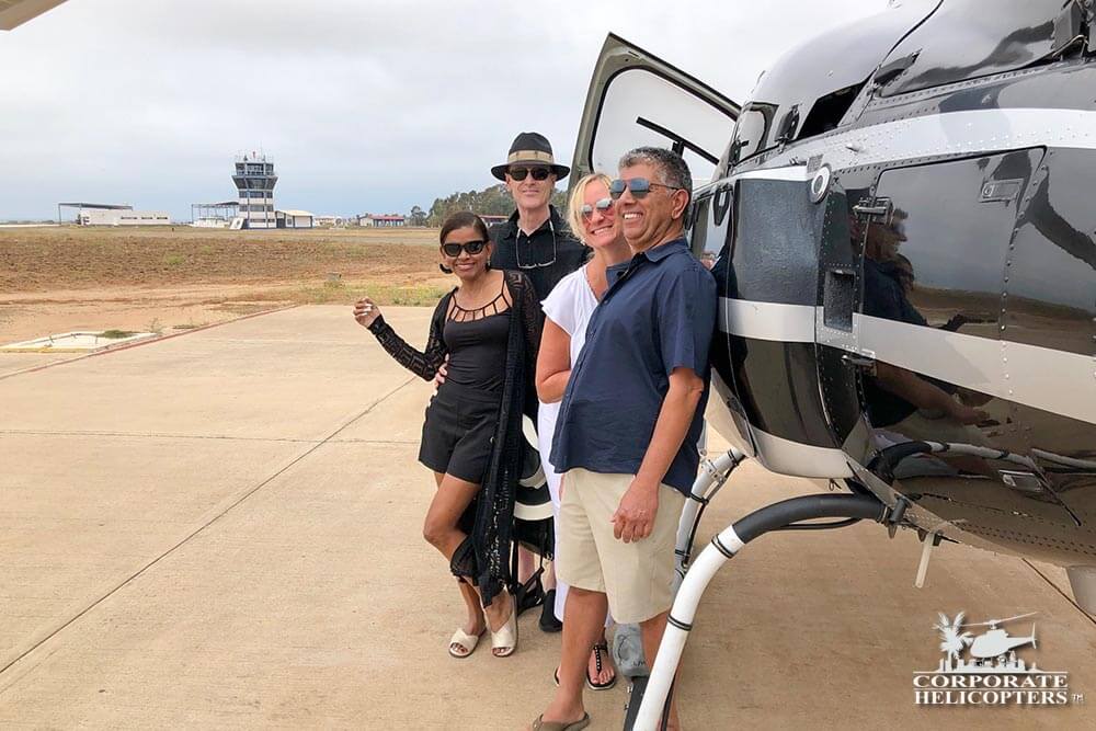 Four people pose by a helicopter on an airfield in Mexico