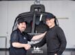 Two men shake hands in front of an Airbus helicopter