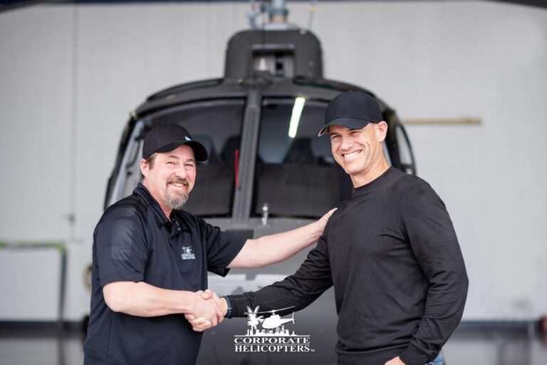Two men shake hands in front of an Airbus helicopter