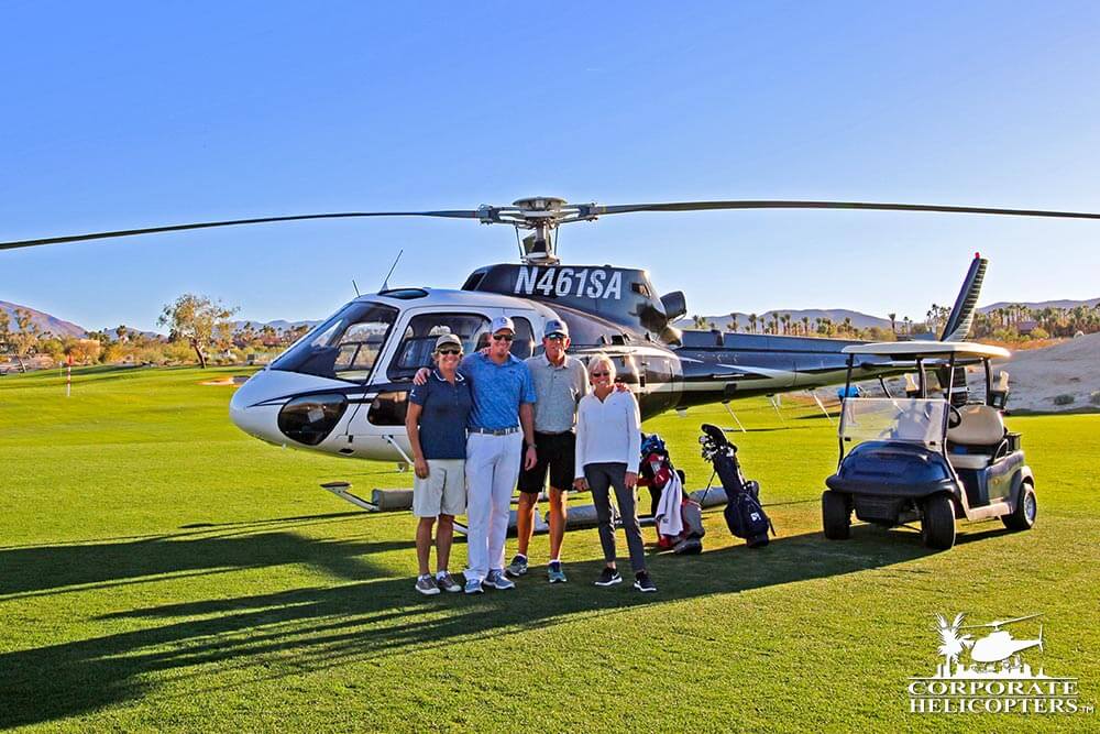 Group poses in front of helicopter on golf course