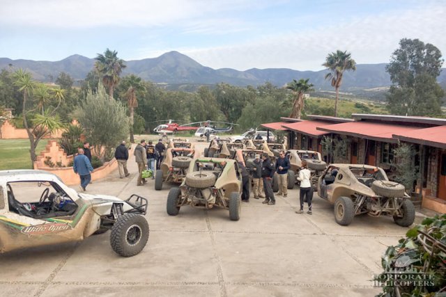 A group of off road race vehicles in front of a house