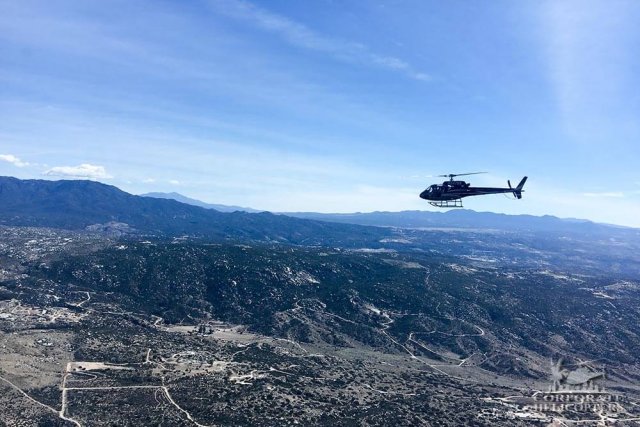 A helicopter flies above rocky desert terrain