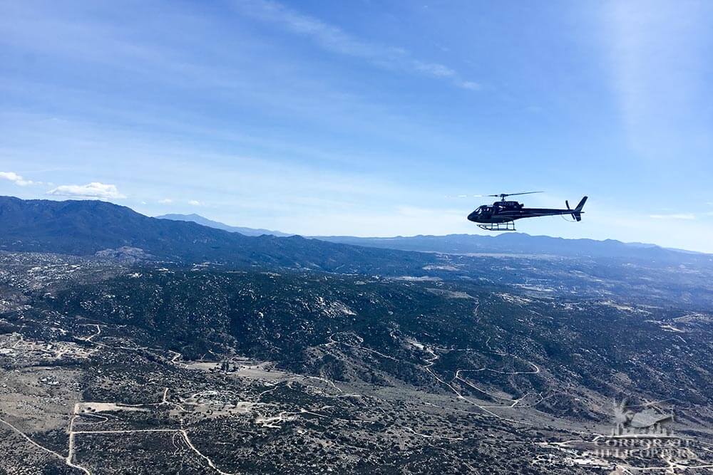 A helicopter flies above rocky desert terrain