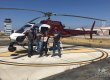 four people stand next to a helicopter