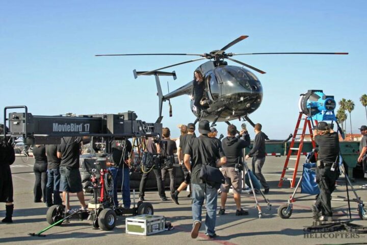 Woman stepping out of a helicopter on a crowded production set