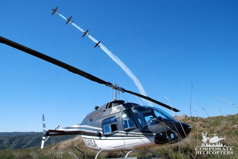 4 stunt planes flying over a helicopter landed on the ground