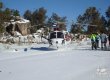 A helicopter landed in the snow, people stand next to it