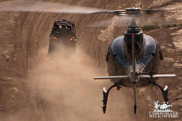 Helicopter chases a race car in the desert