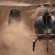 A helicopter chases an off road race vehicle in the desert