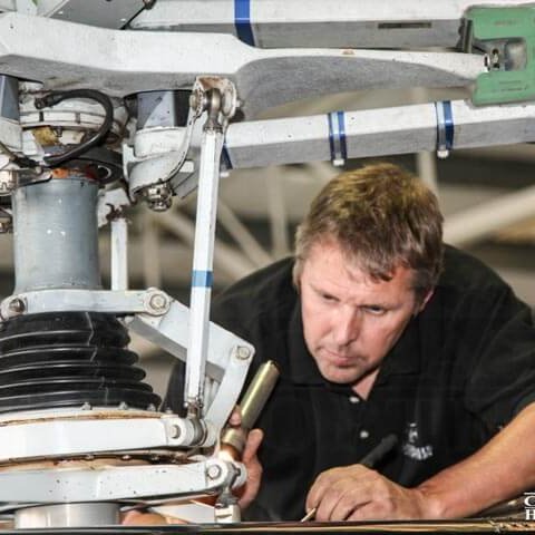 Man performing maintenance on helicopter rotor