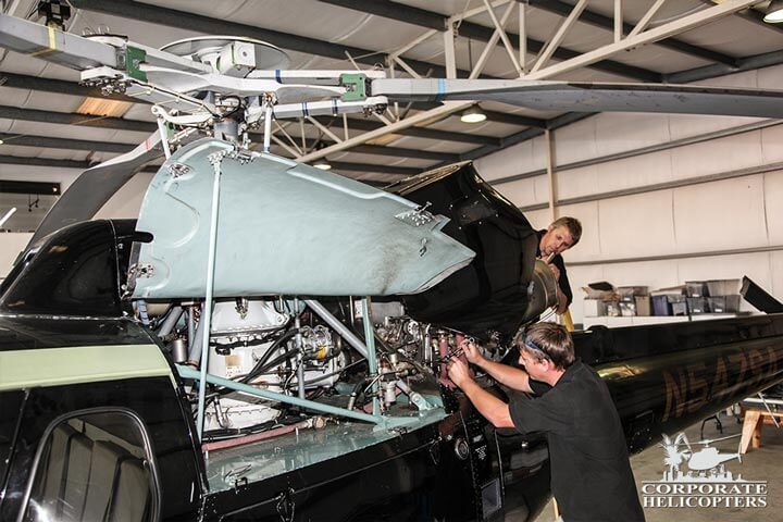 Helicopter being repaired by two technicians