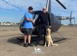 Jim McCoy shakes Ivor Shier's hand in front of a new Robinson R44 Raven Il. A dog sits next to Ivor.