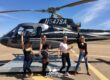 Four women posing in front of a helicopter