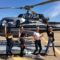 Four women posing in front of a helicopter