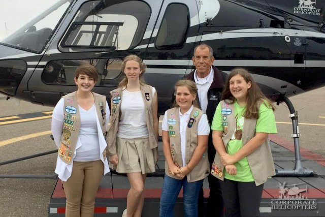 Girl Scouts pose in front of a helicopter