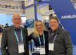 Ivor & Deann Shier pose for a photo with Tim Hutter in front of an Airbus display at the 2022 HAI Heli-Expo