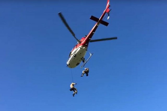 2 stuntmen rappel out of a helicopter in flight