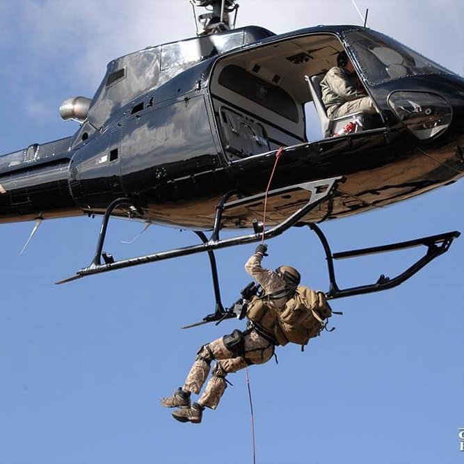 Man in Military-esque clothing repelling from a helicopter