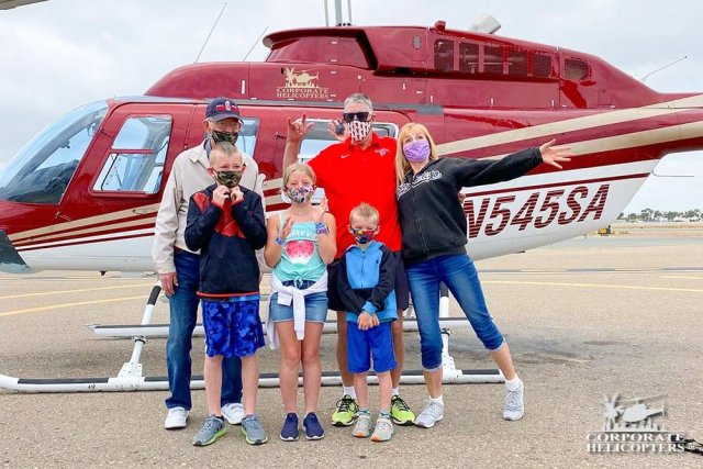 A 6-member family poses in front of a helicopter