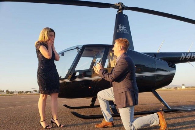 Man proposing to fiancee in front of helicopter