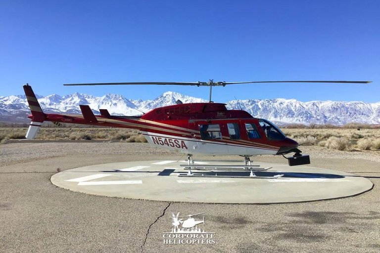 A LiDAR mapping helicopter landed in Bishop, California with snow-covered mountains in the background.