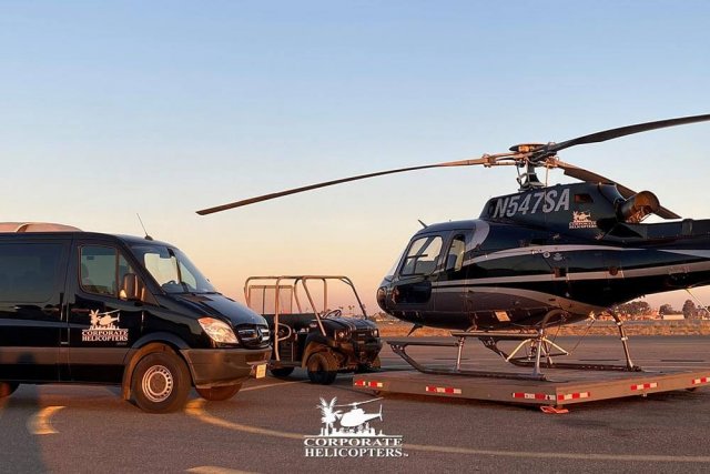 Helicopter on landing pad, a van and modified golf cart next to it.