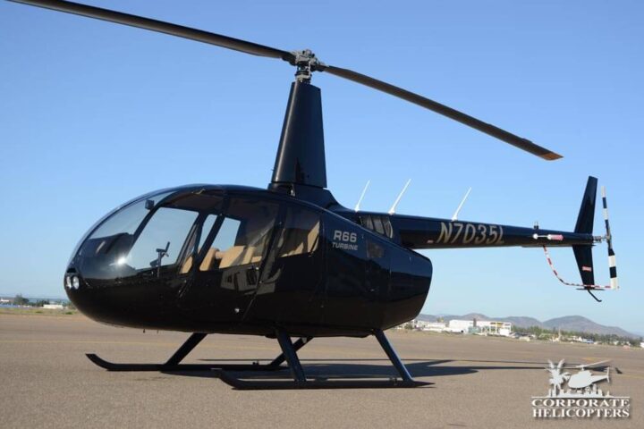 A black 2014 Robinson R66 helicopter on an airfield