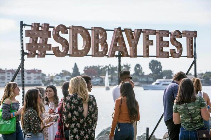 Candid photo of people and a sign that reads #sdbayfest
