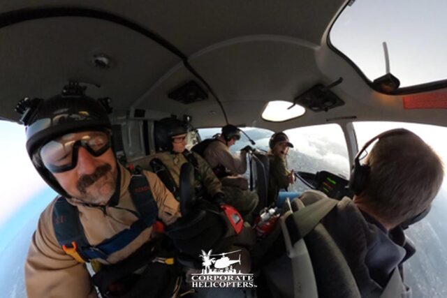 Skydivers prepare to jump out of a helicopter