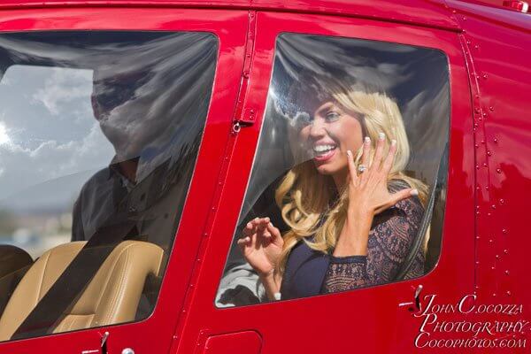 A newly engaged woman smiles brightly and shows off her ring inside of a helicopter