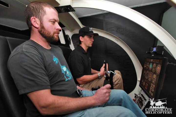2 students inside of a helicopter flight simulator