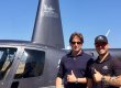 Pilot and travel writer pose for photo in front of helicopter