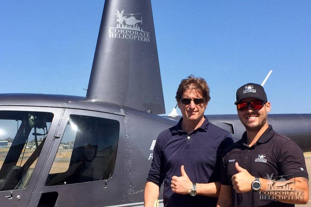 Pilot and travel writer pose for photo in front of helicopter
